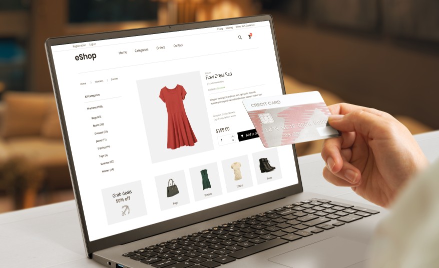 A person buying a red dress from an online store using a laptop